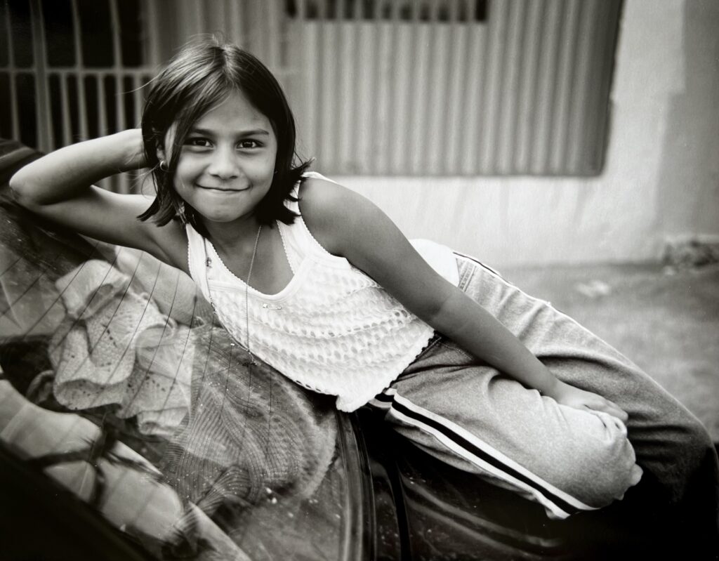 Young girl on a car, San Jose, Costa Rica (1998) by photographer Russell Levin.