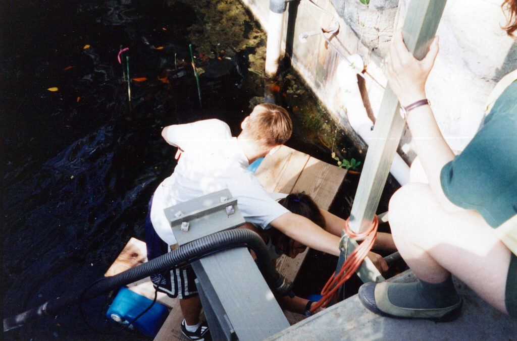 Michael Aaron Gallagher climbs onto the makeshift raft to collect data in the freshwater pond of the Marsh Biome inside the Biosphere 2 Center in 1998.