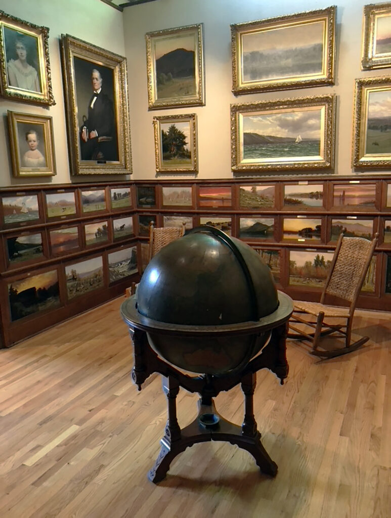 Globe and oil paintings on display at the John D Barrow Art Gallery in Skaneateles NY by Michael Aaron Gallagher